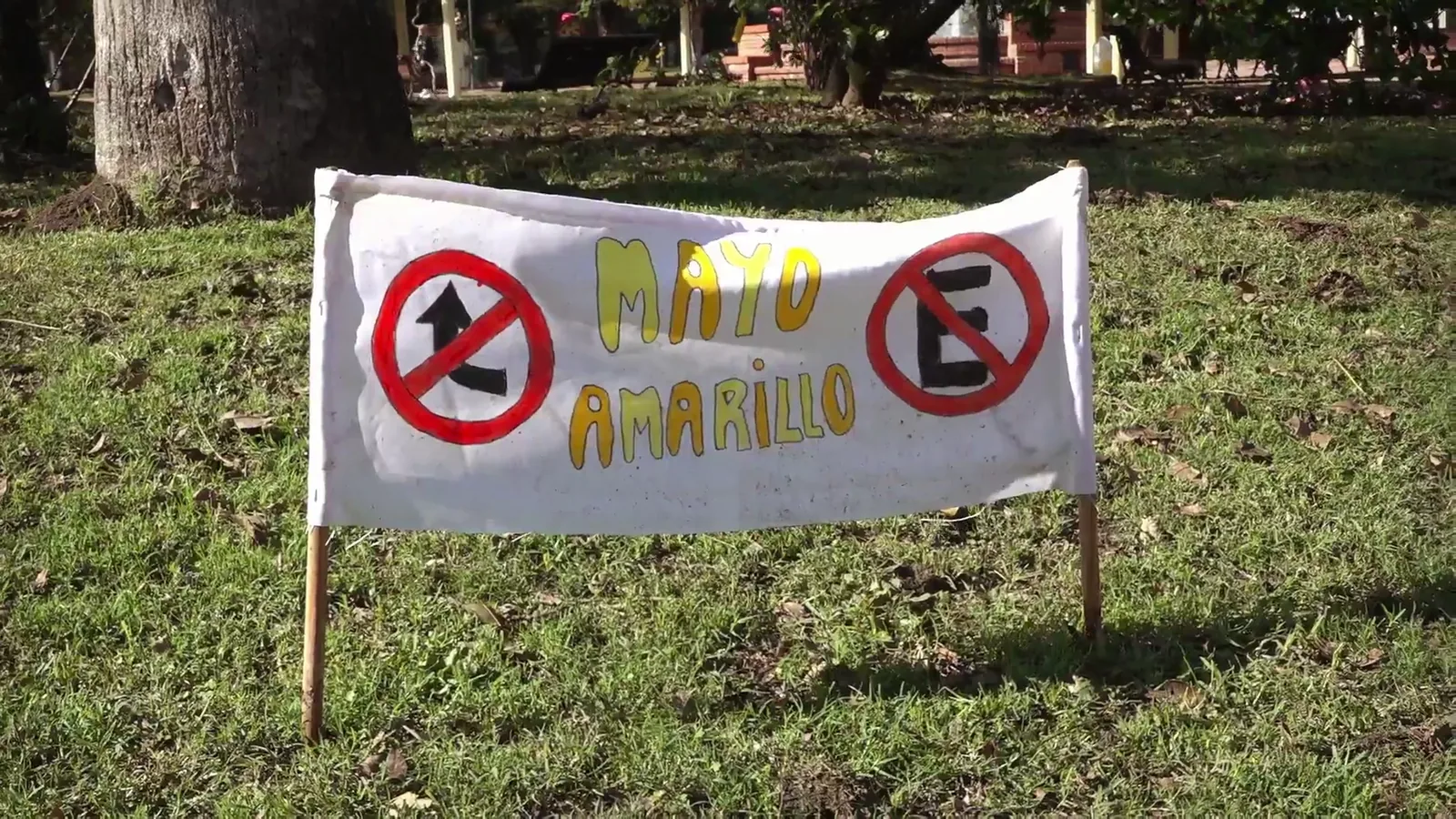 Cartel pintado a mano con la palabra Mayo Amarillo y dos señales de tránsito en la plaza de Tala, Canelones, 2025