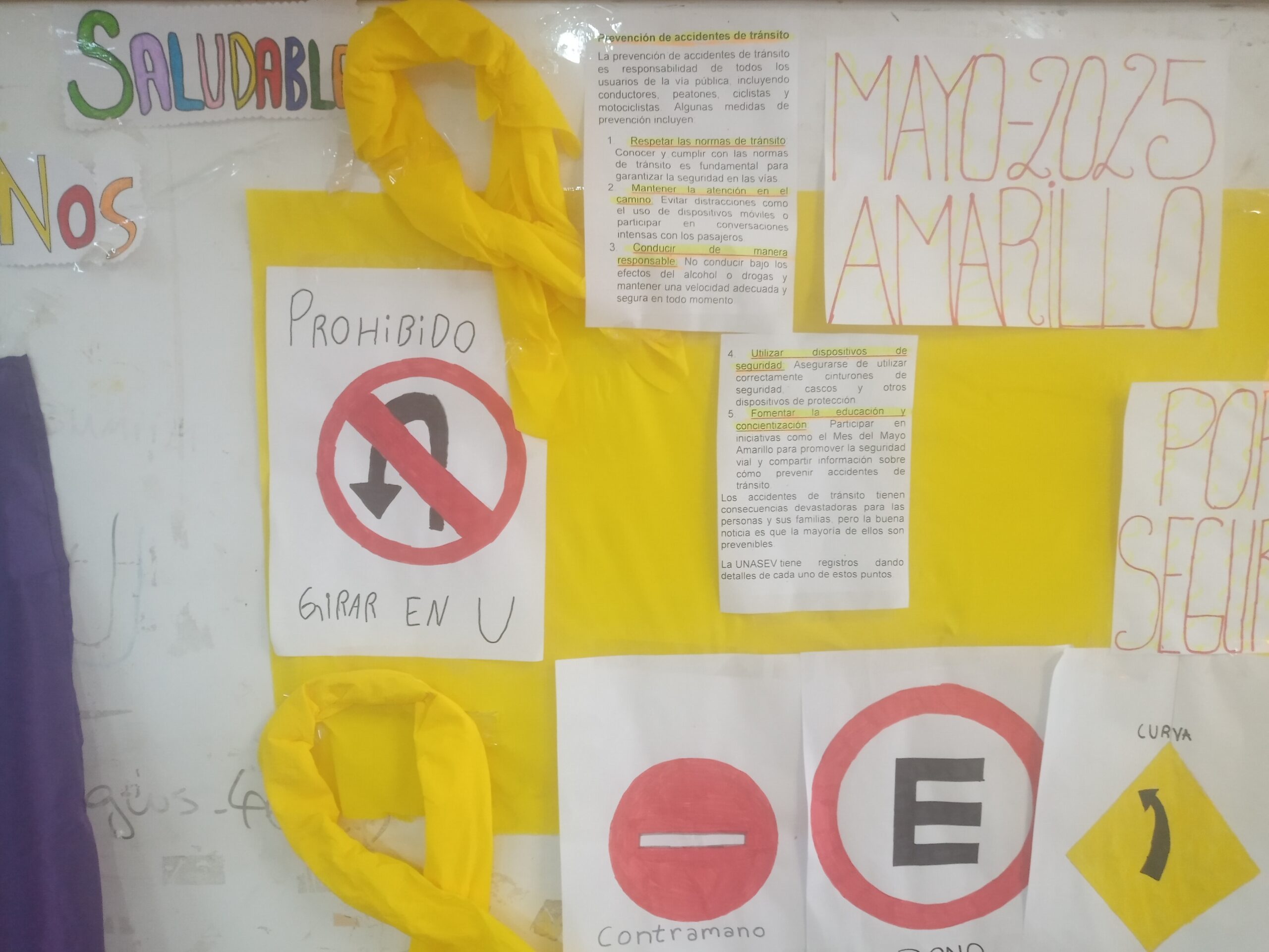 Señales de prohibido girar en U y contramano junto a lazos amarillos en la cartelera del Liceo 3 de Shangrilá