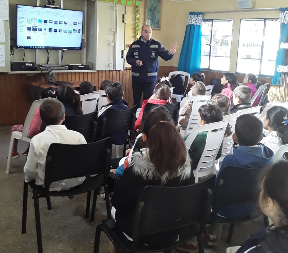 Mayo Amarillo en Tranqueras 6 Un inspector de tránsito da una charla junto a una pantalla a escolares sentados en un salón de Tranqueras