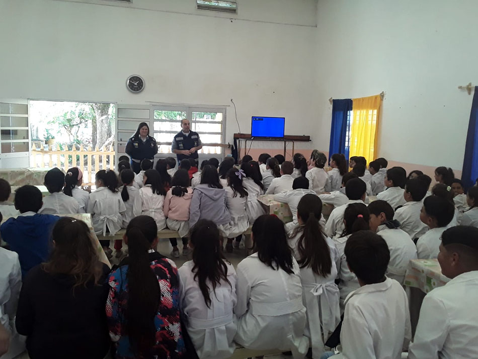 Escolares de túnica blanca sentados en un salón de una escuela de Tranqueras durante la charla de dos integrantes de Tránsito