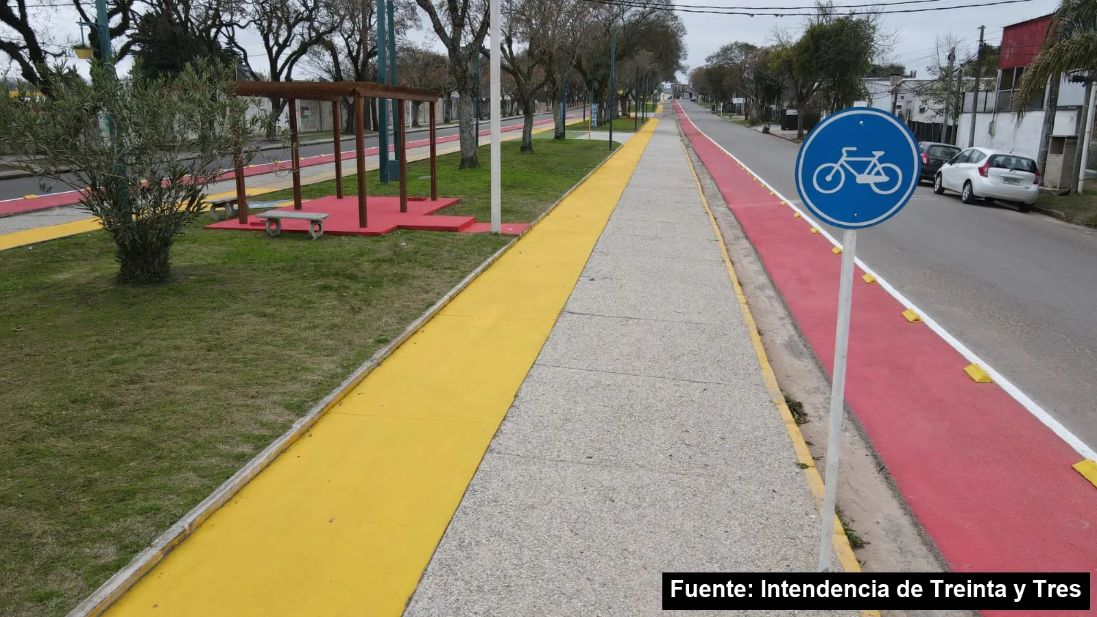 Ciclovía roja con cartel de bicicletas junto a una senda peatonal con bordes amarillos en la avenida Brasil
