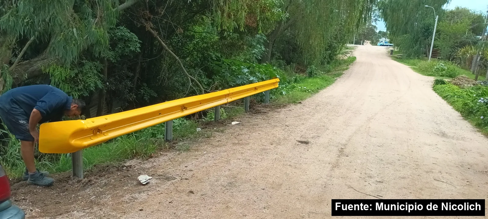Mayo Amarillo en Colonia Nicolich 5 Trabajador del Municipio ajustando un guardarrail amarillo junto a una calle de tierra en Nicolich