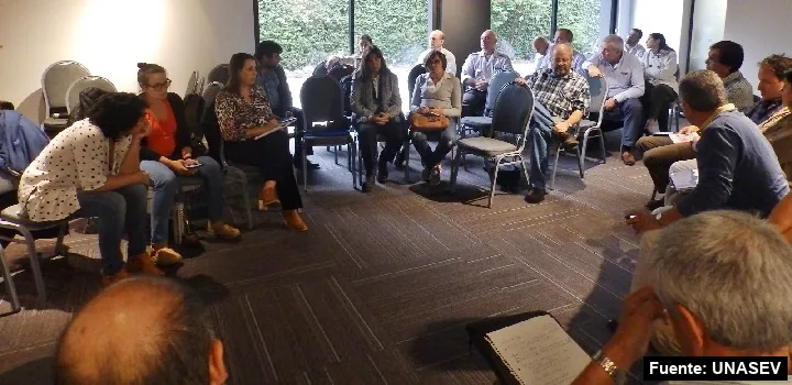 Representantes de organizaciones sentados en ronda en un salón, en una reunión de coordinación de Mayo Amarillo.