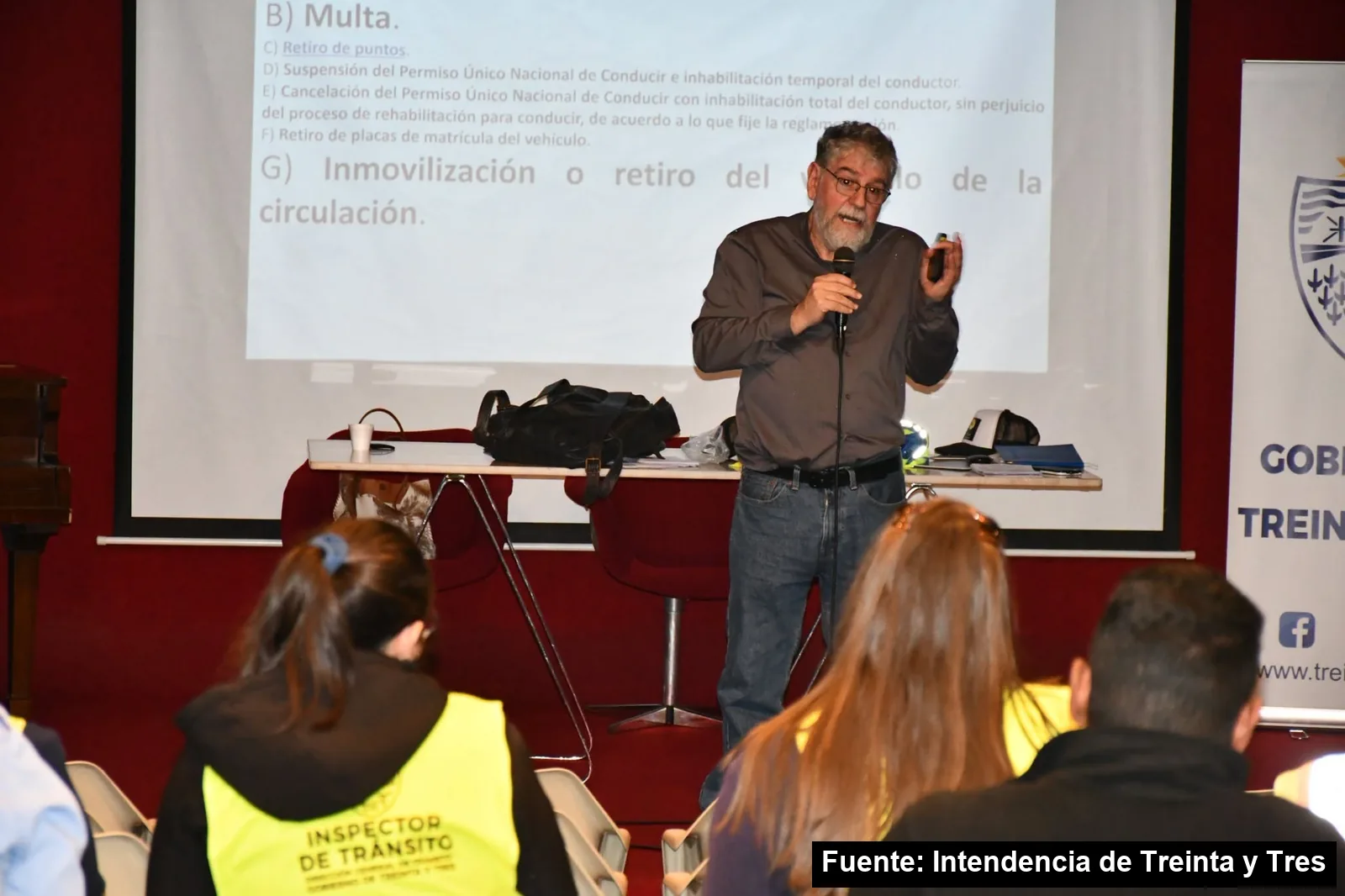 Un docente explica normas de tránsito frente a una pantalla a inspectores con chalecos reflectivos, en la capacitación de la Intendencia de Treinta y Tres