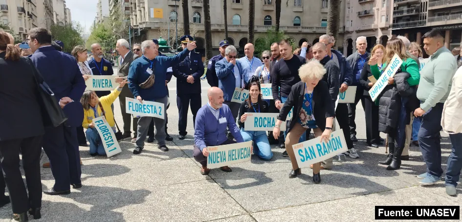 Integrantes de unidades locales de seguridad vial con carteles de sus localidades en una plaza de Montevideo