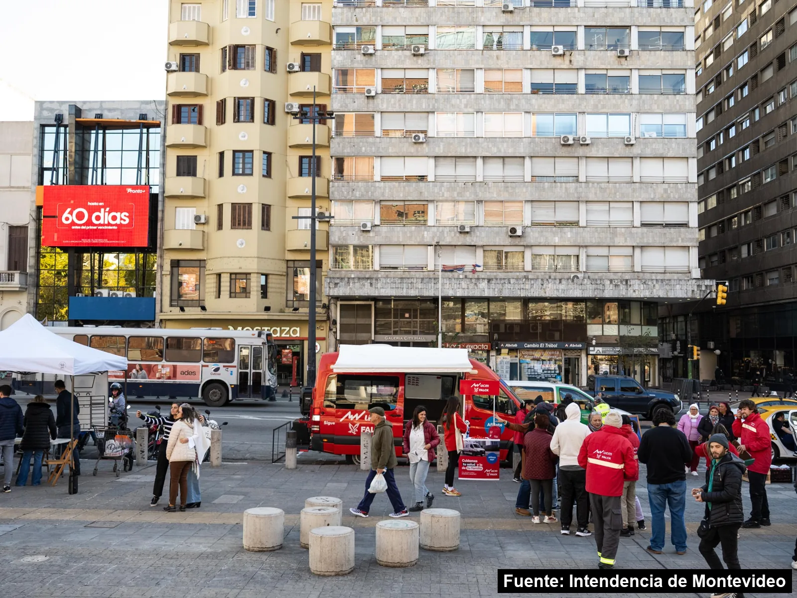 Vista amplia de la explanada de la Intendencia de Montevideo con carpas, una unidad de emergencia y público
