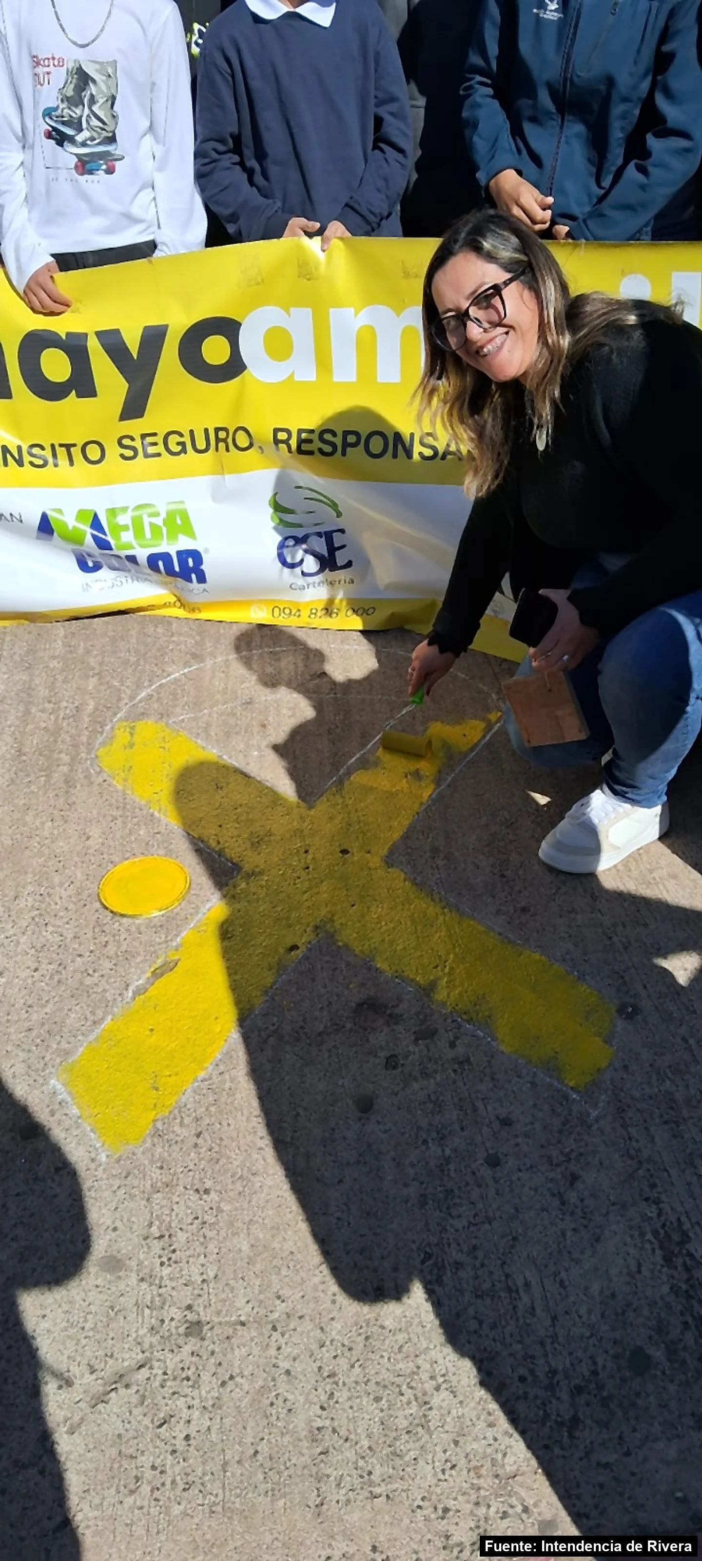 Mayo Amarillo en Tranqueras 2 Una mujer pinta con rodillo un lazo amarillo en la calle frente al pasacalle de Mayo Amarillo, en Tranqueras