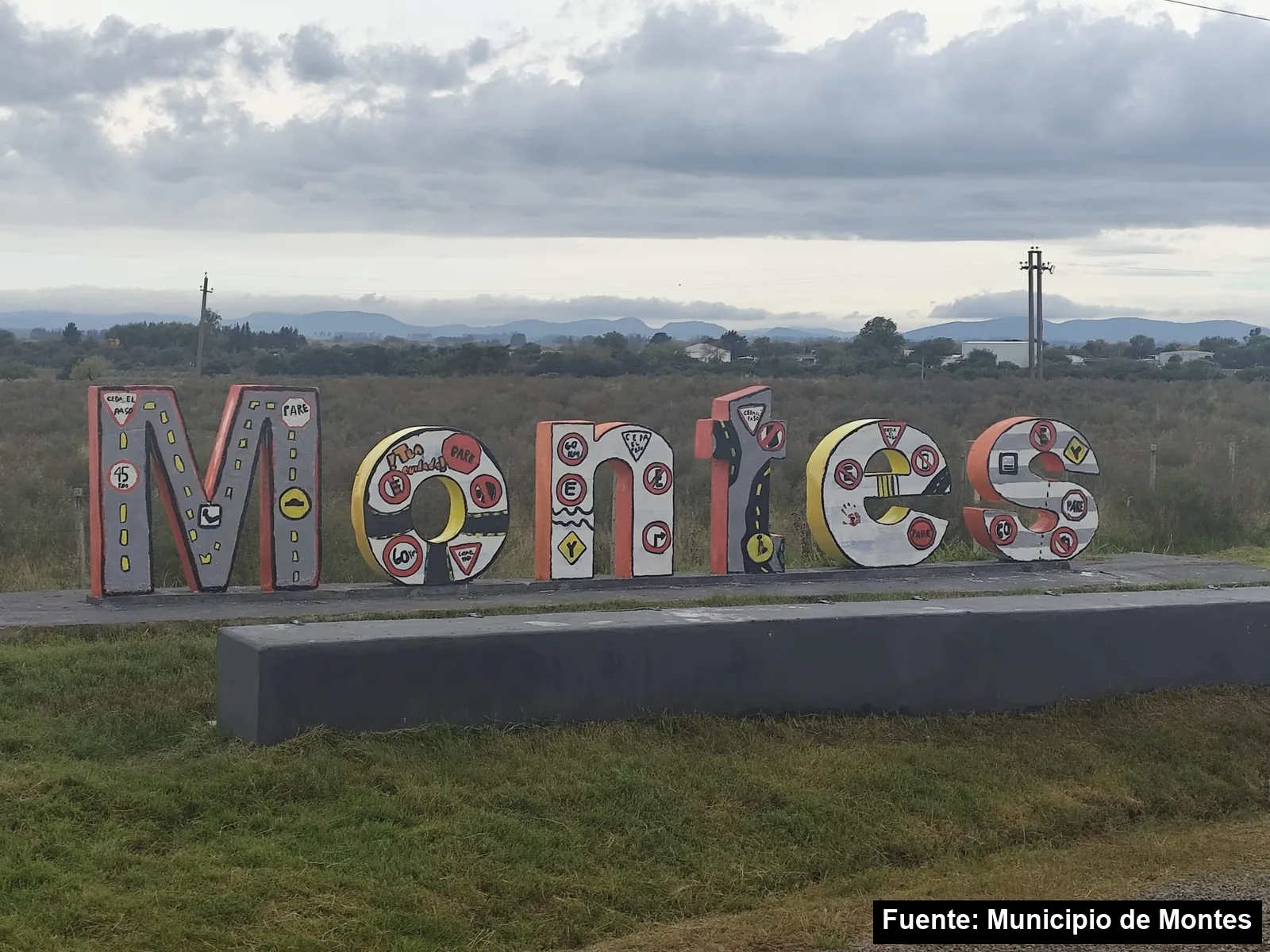 Letras con el nombre de Montes pintadas con señales de tránsito por estudiantes del liceo, con las sierras al fondo