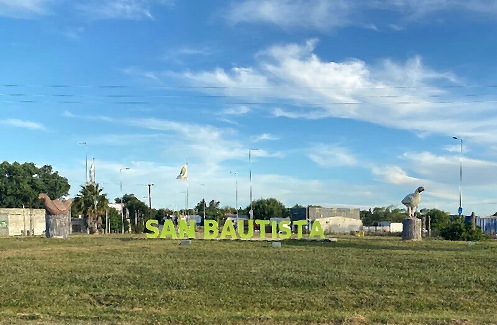 Letras de San Bautista junto al monumento al pollo y la gallina