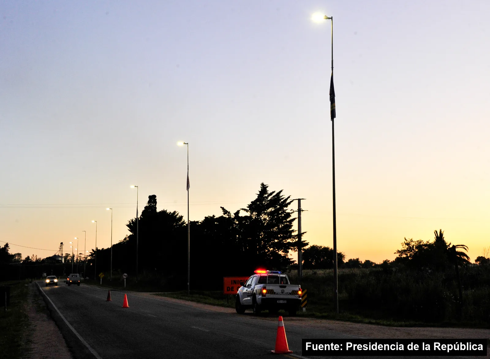 Columnas de luz nuevas encendidas al atardecer a lo largo de una ruta en Toledo, Canelones