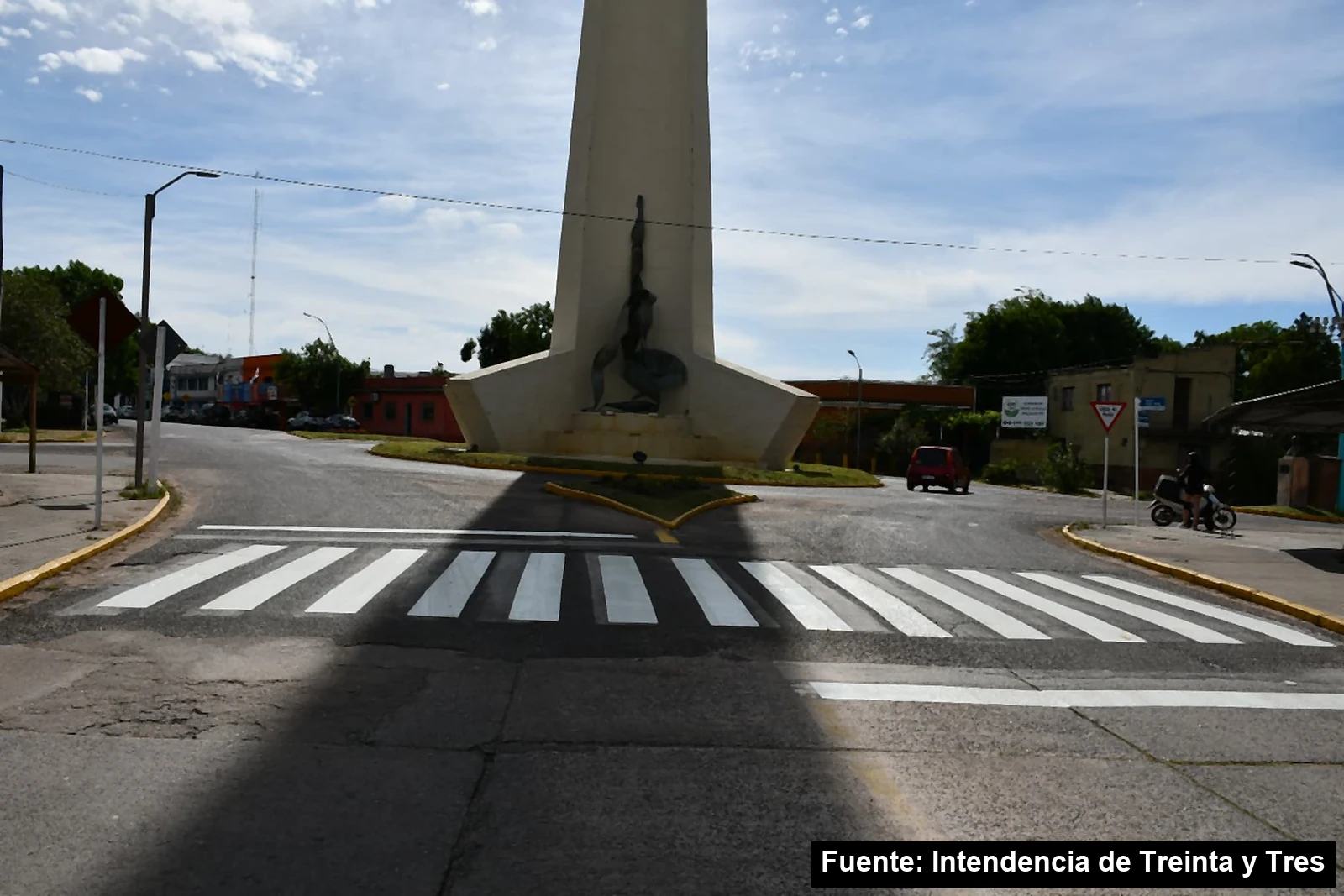 Senda peatonal blanca recién pintada frente al obelisco de una rotonda de Treinta y Tres