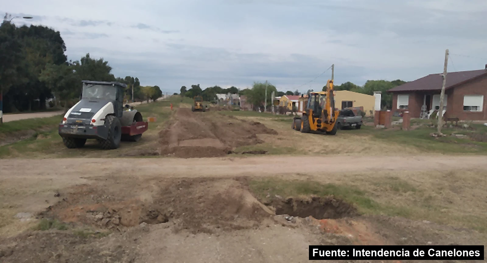 Mayo Amarillo en San Bautista 2 Máquinas viales trabajando en el Camino Nacional de San Bautista, con casas a un lado y la calzada en obra