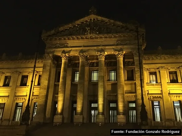 La fachada del Palacio Legislativo de Montevideo, iluminada de amarillo de noche.