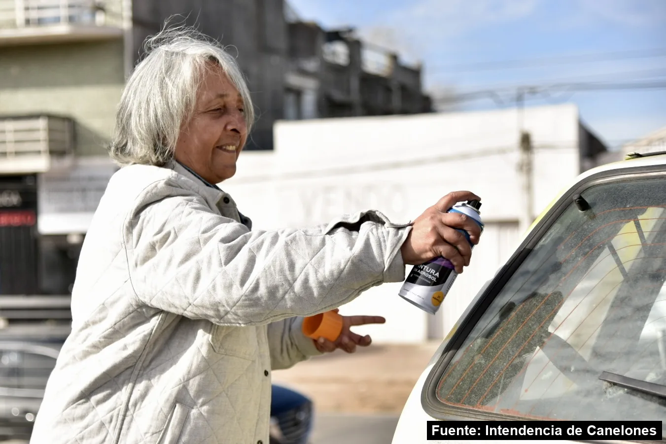 Una vecina pinta con aerosol el vidrio de un auto siniestrado frente al CeReSur de Las Piedras, mayo de 2025