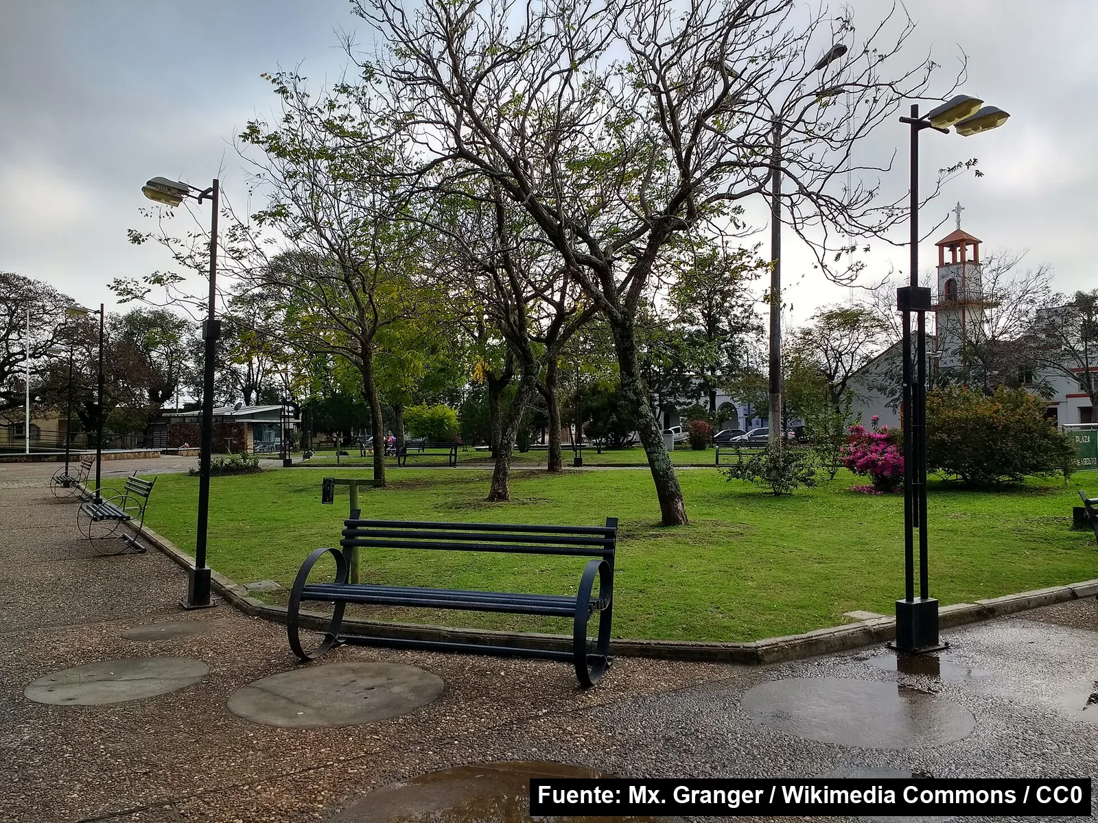 La plaza 25 de Agosto de Bella Unión, con bancos, faroles y árboles, y el campanario de una iglesia al fondo