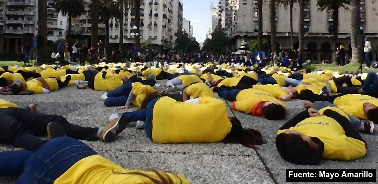 Intervención de Mayo Amarillo en la Plaza Independencia de Montevideo: personas con remeras amarillas acostadas en el piso