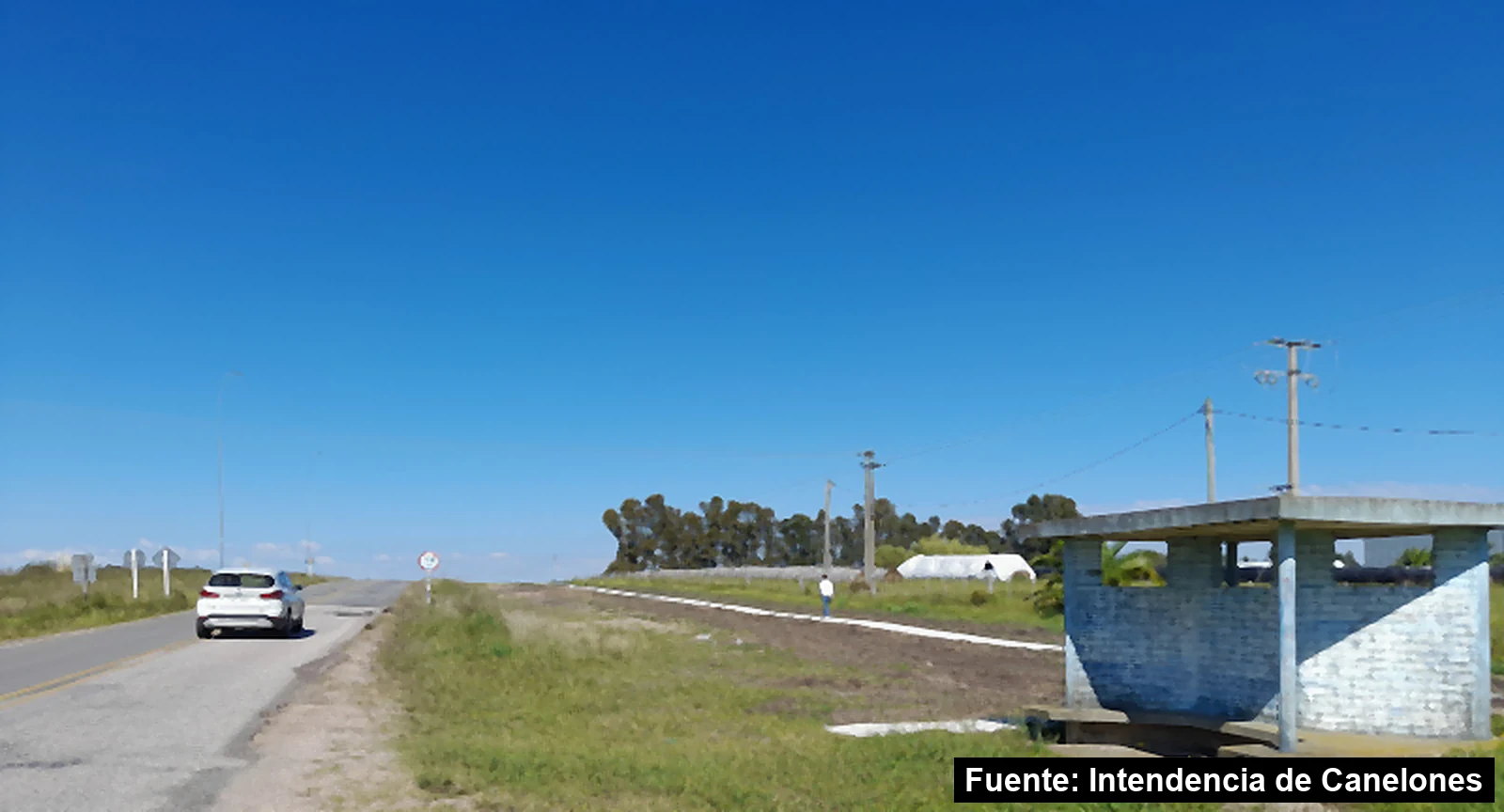 Refugio peatonal junto a la ruta, con la senda nueva detrás y una persona caminando por ella, en San Antonio