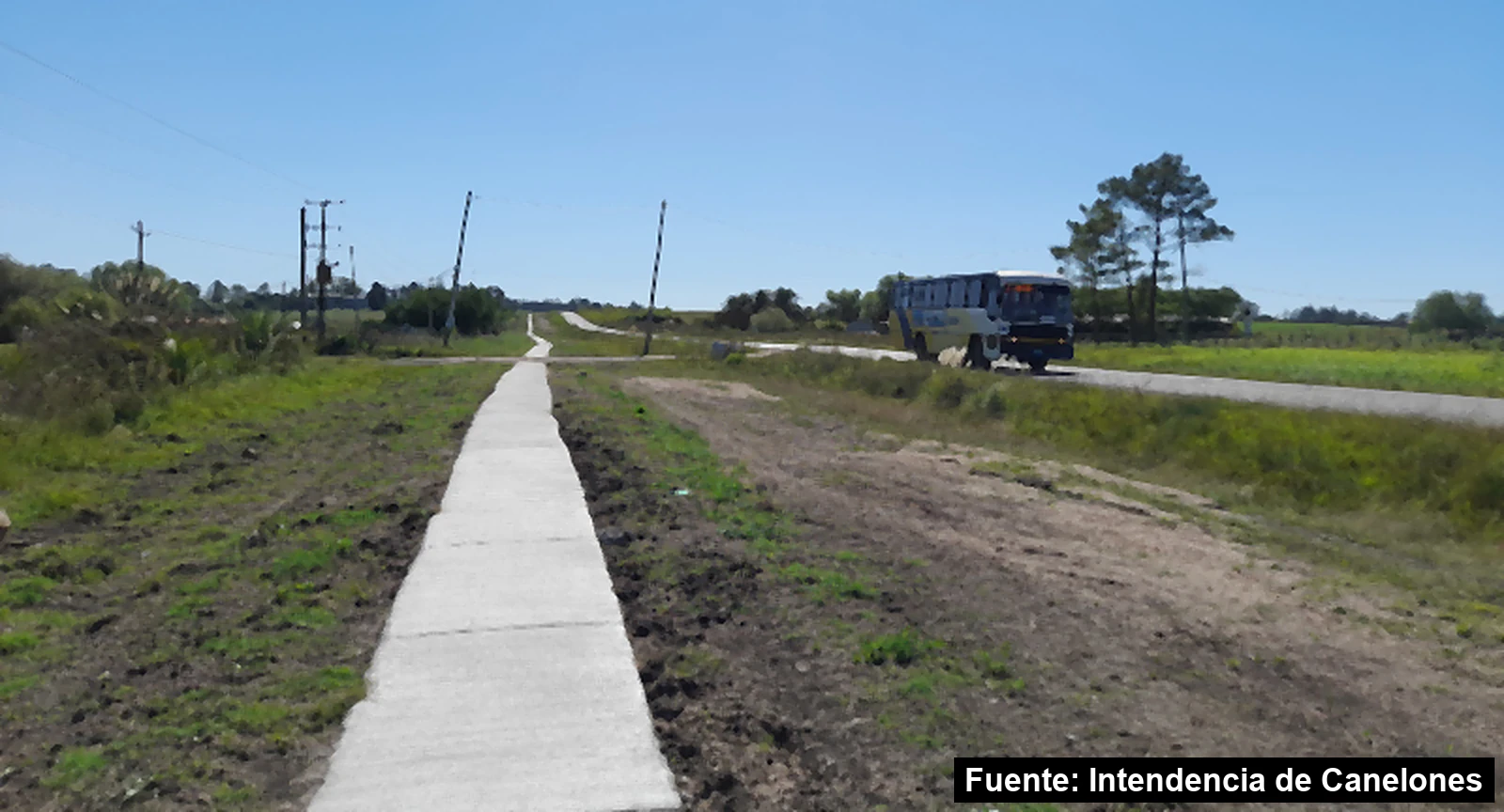 Mayo Amarillo en San Antonio 8 Senda peatonal de hormigón junto a la ruta de acceso a San Antonio, Canelones, con un ómnibus que pasa por la ruta