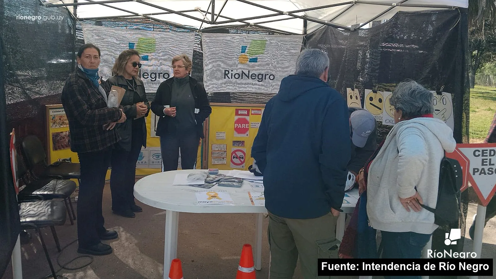 Vecinos consultan en el stand de educación vial de San Javier, con un folleto de Mayo Amarillo sobre la mesa